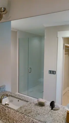 A large mirror installed on the wall over a granite bathroom countertop by Glass Doctor of Nashville.