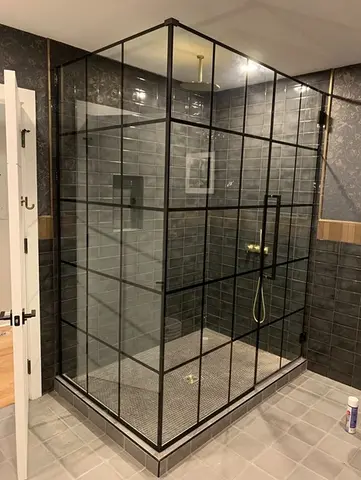 A corner shower with dark gray tiles and a black-framed glass enclosure on two sides from Glass Doctor of Nashville.