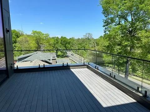 A glass panel railing with a metal top frame surrounding a porch by Glass Doctor of Nashville.