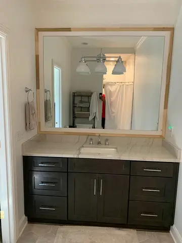 Mirror with wood frame mounted over a vanity with marble countertop from Glass Doctor of Nashville.