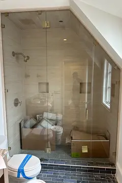A fully-enclosed shower with an angled wall, floor-to-ceiling frameless glass panels and a swinging door by Glass Doctor of Nashville.