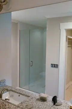 A large mirror installed on the wall over a granite bathroom countertop by Glass Doctor of Nashville.