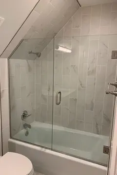 Frameless glass shower door panels with a swinging door installed by Glass Doctor of Nashville on a tub.