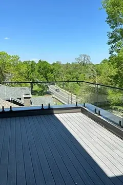 A glass panel railing with a metal top frame surrounding a porch by Glass Doctor of Nashville.